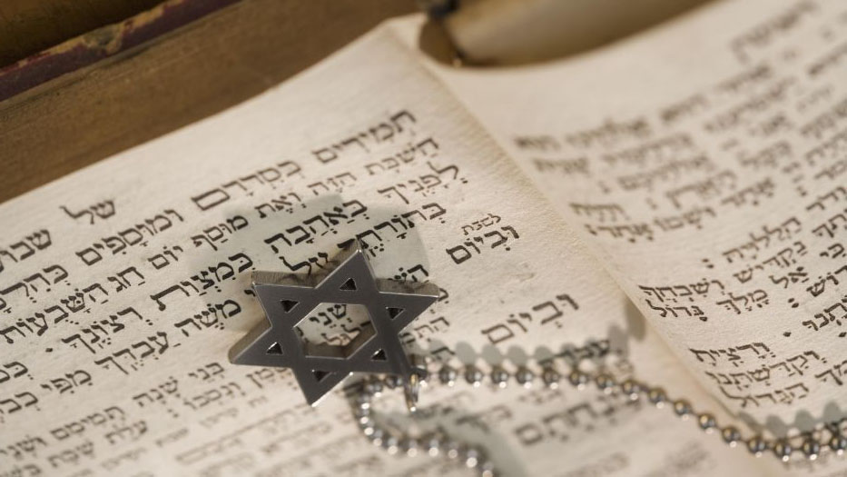 Aufgeschlagenes hebräisches Buch, darauf liegt eine silberne Kette mit Davidstern-Anhänger